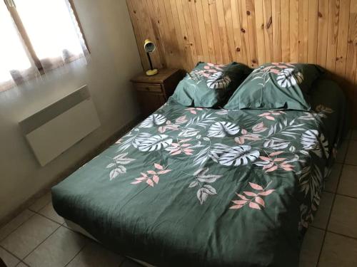 a bedroom with a bed with a green comforter at Chalet rouge gorge in Mars