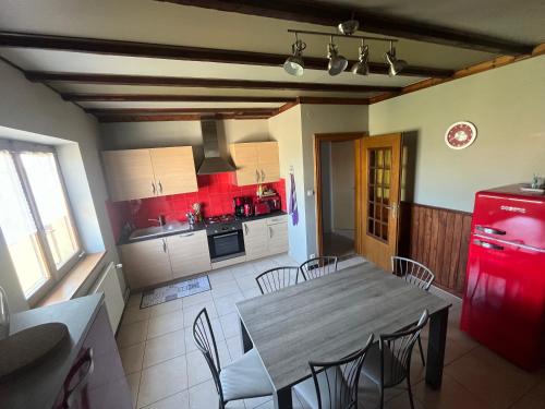 Il comprend une cuisine équipée d'une table, de chaises et d'un réfrigérateur rouge. dans l'établissement Gîte aux écuries Cerio, à Saint-Hippolyte