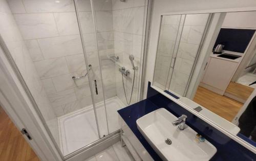 ein weißes Bad mit einer Dusche und einem Waschbecken in der Unterkunft 5* Hotel Orbi City in Batumi