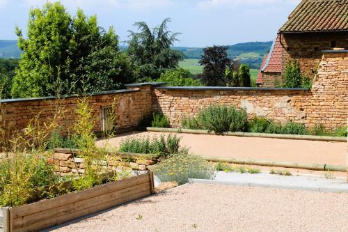 a garden with a brick wall and a stone fence at LE CLOS DES PIERRES ROUGES in Burgy