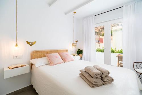 a white bedroom with a bed with towels on it at Casa Bonita in Almería