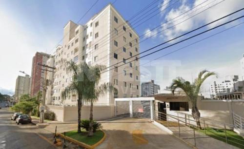 a large white building in a city with palm trees at Apartamento Aconchegante in Goiânia