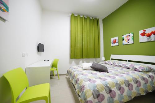 - une chambre avec un lit, un bureau et un mur vert dans l'établissement Affittacamere Arcobaleno, à Trapani