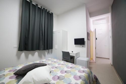 a bedroom with a bed and a desk and curtains at Affittacamere Arcobaleno in Trapani