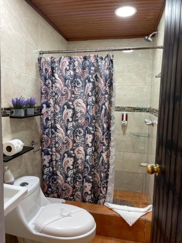a bathroom with a shower curtain and a toilet at Cabinas Vista Al Golfo in Monteverde Costa Rica
