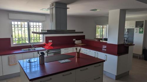 cocina con armarios blancos y encimera roja en El Collado, en Cullera