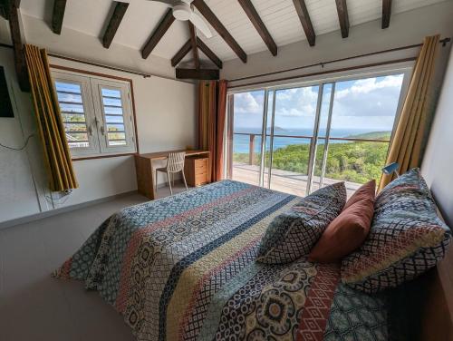 una camera da letto con un letto e una grande finestra di Villa Perséides a Deshaies