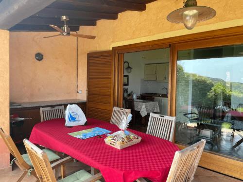 una mesa de comedor con un mantel rojo y sillas en CAPO CODA CAVALLO VILLA SALINEDDA GIARDINO VISTA MARE, en Capo Coda Cavallo