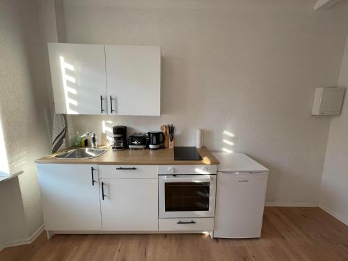 Apartment Mirabelle 2 في Püttlingen: مطبخ صغير مع دواليب بيضاء ومغسلة