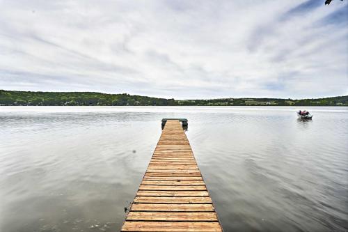 a dock on a lake with a boat in the water at Happys Haven Cabin with Gas Grill and Fire Pit! in Lodi