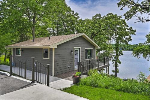 a tiny house with a porch next to a lake at Happys Haven Cabin with Gas Grill and Fire Pit! in Lodi