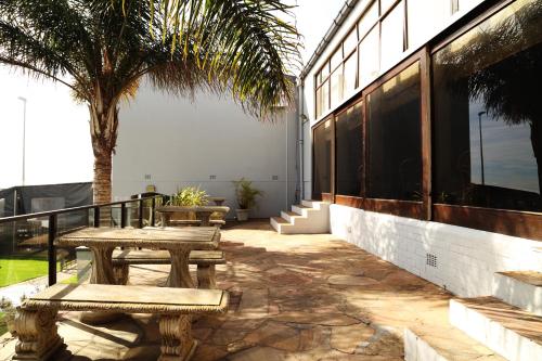 a patio with benches and a palm tree next to a building at Hotel Portao Diaz in Mossel Bay