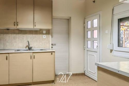 kuchnia z białymi szafkami, umywalką i oknem w obiekcie Volos Cental House w mieście Wolos