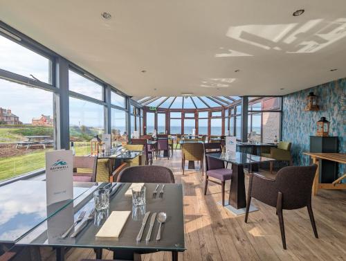 un restaurante con mesas, sillas y ventanas en Bayswell Park Hotel, en Dunbar