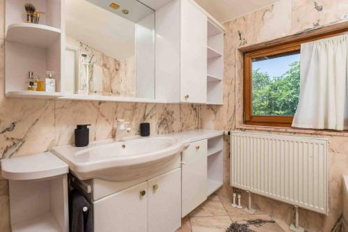 a white bathroom with a sink and a window at Villa The Nest in Opatija