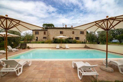 a swimming pool with white chairs and umbrellas at Casale Rancaglia in Gubbio