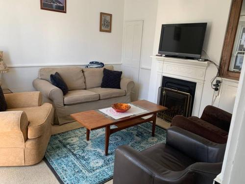 a living room with a couch and a table and a fireplace at Vine Cottage - Sandgate in Sandgate