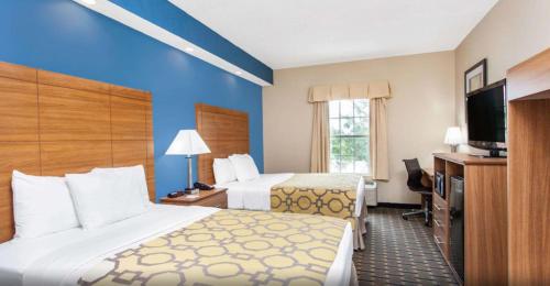 a hotel room with two beds and a flat screen tv at Baymont by Wyndham Jacksonville/Butler Blvd in Jacksonville