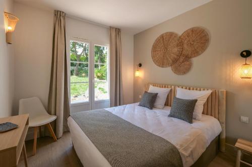 Schlafzimmer mit einem Bett, einem Tisch und einem Fenster in der Unterkunft Chant des Vagues Saint Tropez VIII in Saint-Tropez