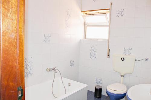 a white bathroom with a toilet and a sink at Villa do Sol Carcavelos Beach House in Carcavelos
