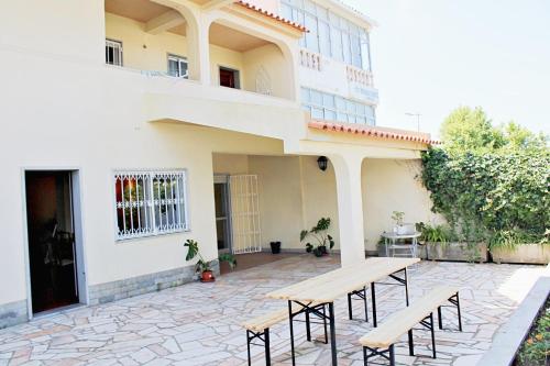 a patio with a wooden table and benches in front of a building at Villa do Sol Carcavelos Beach House in Carcavelos