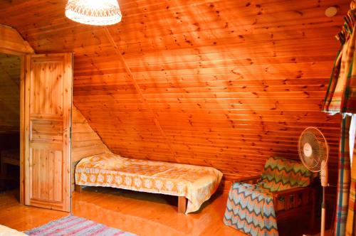 a room with a bed and a chair in a cabin at Luha Talu in Rebaste