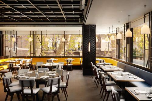 a dining room with tables and chairs and windows at Nobu Hotel London Portman Square in London