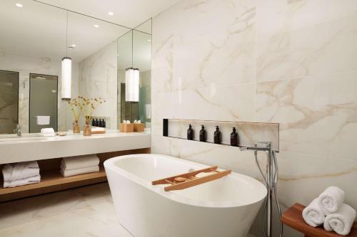 a white bathroom with a tub and a sink at Nobu Hotel London Portman Square in London