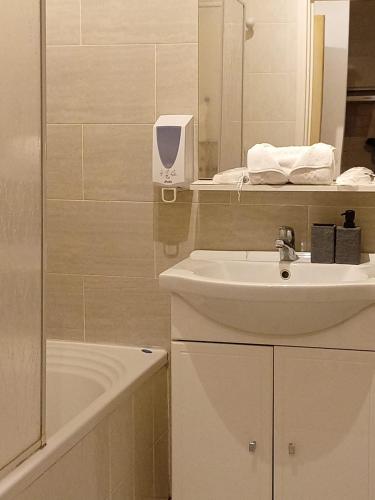 une salle de bain avec un lavabo, un miroir et une baignoire dans l'établissement Meyerbeer YourHostHelper, à Nice
