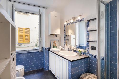 a blue tiled bathroom with a sink and a toilet at Santa Chiara Apartment by Wonderful Italy in Genova