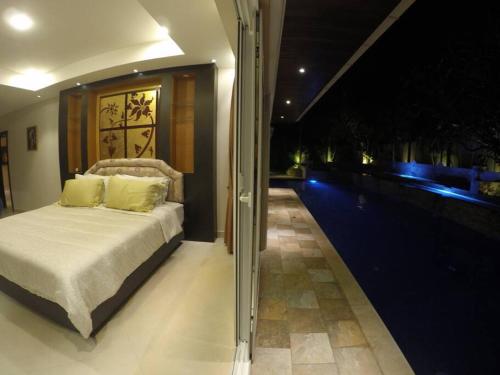 a bedroom with a bed next to a pool at night at 4BRLuxury pool villa near Siam Country club (golf) in Ban Hui Yai Muk