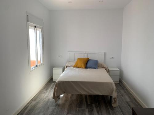 a white bedroom with a bed and a window at Apartamento Cañebolo in La Puebla de los Infantes