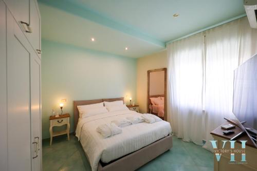 a bedroom with a bed with white sheets and a window at Victory's Luxury House in Ischia