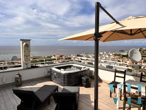 a patio with a hot tub and chairs and an umbrella at Victory's Luxury House with Jacuzzi on the Roof in Ischia