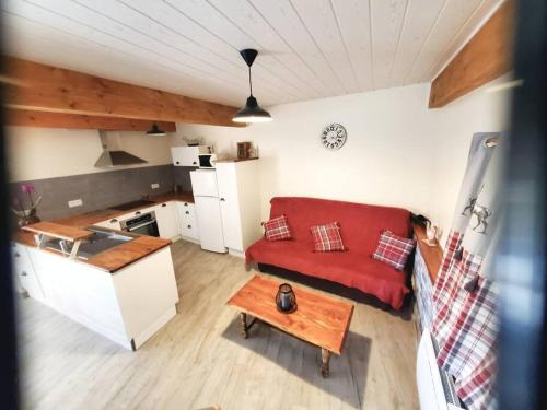 a living room with a red couch and a kitchen at Gite La Grangette de Pauline in Mercus-Garrabet