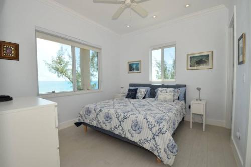 a bedroom with a bed with a blue and white comforter at Cupid's Way is a High-end New Home with Large PRIVATE Pool Snorkeling Cliff Jumping and Water Sports Equipment in Governorʼs Harbour