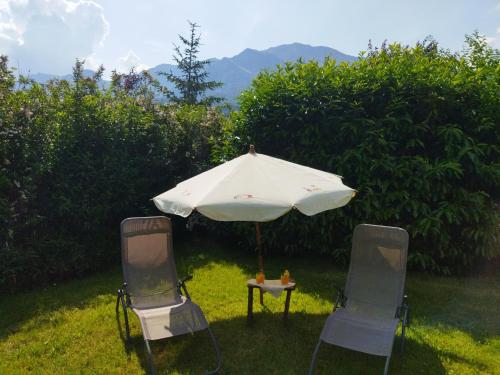 two chairs and a table with an umbrella in the grass at NOMAD ALP B&B in Marthod