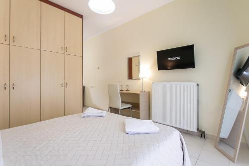 a bedroom with a bed and a desk and a tv at Tranquil Apartments Corfu in Kontokali
