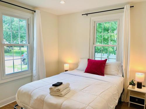 um quarto com uma cama com uma almofada vermelha e 2 janelas em The Drift em Charleston