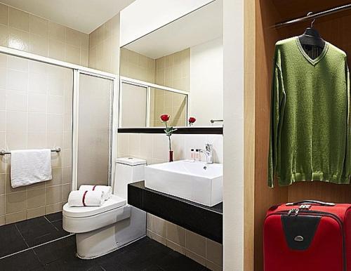 a bathroom with a toilet and a sink and a red suitcase at Sky Hotel @ Selayang in Batu Caves