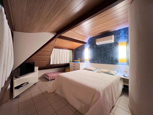 a small bedroom with a bed and a television at Beach Class Resort - Muro Alto Bangalô in Porto De Galinhas