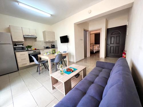 a living room with a blue couch and a kitchen at Antiparos 1 bedroom APT Kyklades in Paralimni
