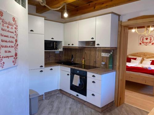 にあるSZÍVES LAKの白いキャビネット付きのキッチン、ベッド1台が備わる客室です。