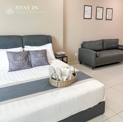 a bedroom with a bed with a couch and a basket on it at Atria Sofo Suites - Petaling Jaya in Petaling Jaya