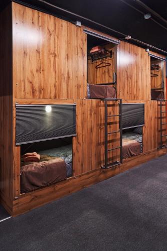 a room with three bunk beds in a wooden wall at Gagarin Capsule Hotel in Almaty