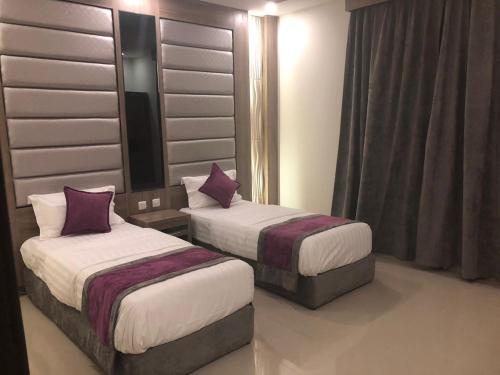 2 Betten in einem Hotelzimmer mit lila Kissen in der Unterkunft Nozol Al Reef by Al Azmy in Riad