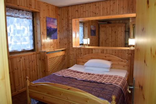 sypialnia z łóżkiem w drewnianym pokoju w obiekcie Arnica w mieście Canazei