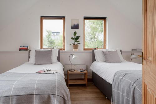 two beds in a room with two windows at The Post House - Seasgair Lodges in Kingussie