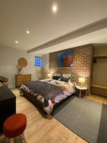 een slaapkamer met een groot bed en een bakstenen muur bij Le gîte 248 in Drucat