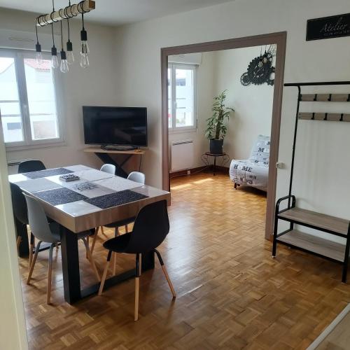 a dining room with a table and chairs and a bedroom at charmante maison entre mer et campagne in La Jarrie